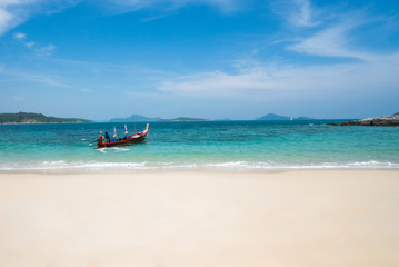 Beautiful panoramic view from sandy beach on longtail boat tied on turquoise sea shore in sunny summer day isolated over blue sky background