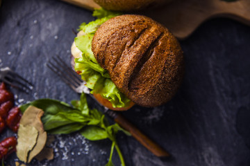 Fast food on the table: hot dog sausage and vegetables, burger with pork or beef and French fries with tomato sauce, basil leaves