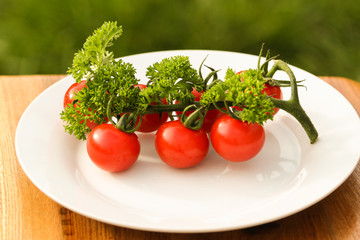 Fresh cherry tomatoes in white plate on wooden table