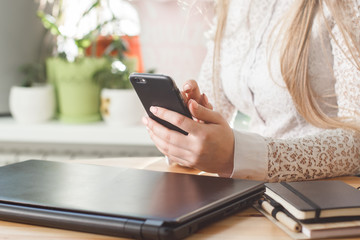 Woman using mobile phone and laptop at home.