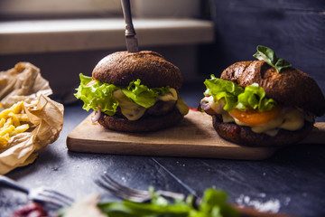 Fast food on the table: hot dog sausage and vegetables, burger with pork or beef and French fries with tomato sauce, basil leaves