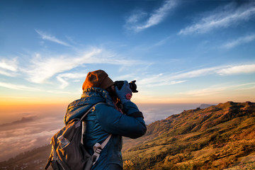 Beautiful women professional photographer takes images with DSLR camera., on the mountain with morning sunlight and fog. - obrazy, fototapety, plakaty