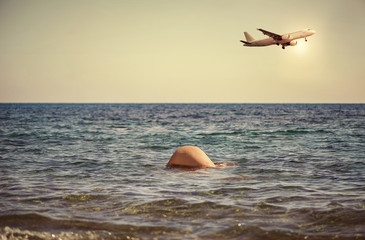 Young girl dives into the sea against the backdrop of the aircraft. Women's buttocks in seawater