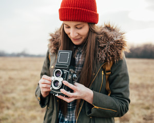 Young hipster girl photographer holding vintage camera