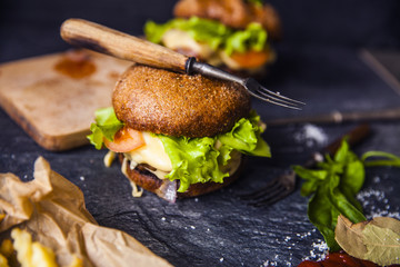 Fast food on the table: burger with beef or pork, or chicken and vegetables, French fries with tomato sauce, basil leaves