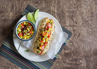 Mexican street style hot dog on wooden background, top view.