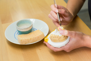 Dental technician applying paint or color to implant or mold