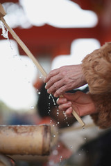 The obligatory ritual washing hands with water from the bucket in front of entrance to the Shinto...