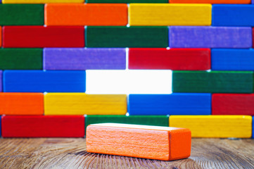 Abstract wall or barrier of multicolored wooden blocks, through which the light shines. Success concept. Business metaphor. Move beyond meaning or definition. Wall of wooden blocks without one piece.
