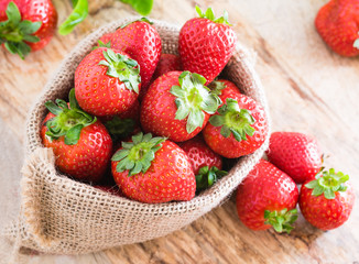Red fresh strawberries in burlap sack
