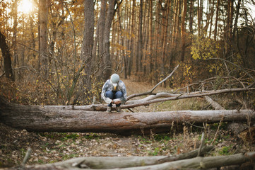 hipster man in a rubber pigeon bird mask standing in the autumn sunset forest