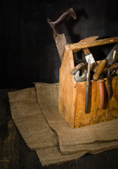 Old used tools in the toolbox. Dark background. spot lighting. Wooden box. Repair work.