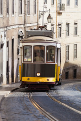 Fototapeta na wymiar Vintage yellow tramway in Lisbon, Portugal. Bright tram on neutral background building. Tram edit up