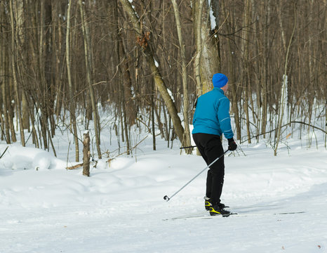 The man on the cross-country skiing in winter forest.