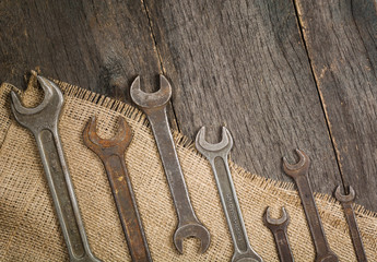 old and rusty spanners on a background of a wooden table and sacking