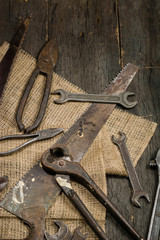 Many old rusty tools scattered on the wooden tstolu. View from above.