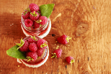 Fresh ripe raspberry in glass bottles on brown background. Copy space. Close up. Top view.