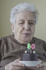 Senior woman blowing candle of her birthday cake