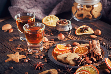Whiskey or liqueur, cookies, spices and decorations on wooden background.