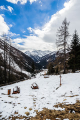 Mountain winter landscape. A valley and mountains covered with snow in Val di Rabbi / Rabbi Valley, Trentino alto adige. The sky is clear but with clouds