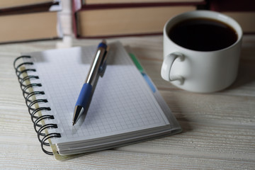 note pad and pen on a table littered with books and cup of coffee. Preservation of records.