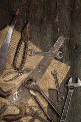 Many old rusty tools scattered on the wooden tstolu. View from above.