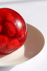 round red  jelly with raspberries on a white plate on a light background