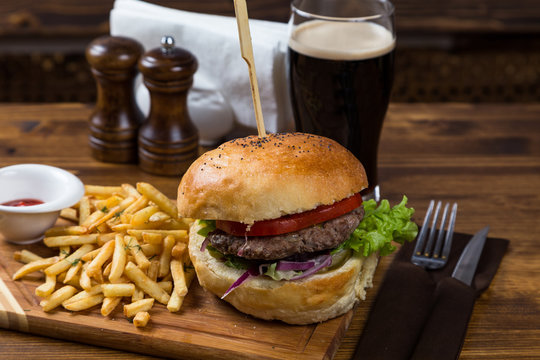 hot burger serving on wooden board with dark beer