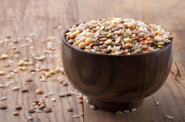 The mixture of different lentils and rice in a wooden bowl