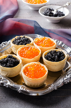 Black and red caviar tartlets, appetizer canapes on silver tray