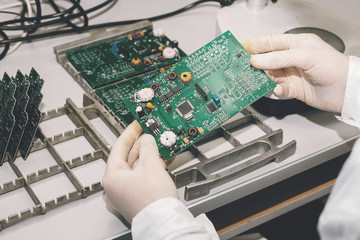 Fototapeta na wymiar The technician takes a computer board with chips. Spare parts and components for computer equipment. Production of electronics and maintenance. The concept of high technology and robotics.