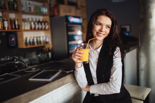 Healthy eating - young woman keeping orange juice at restaurant bar
