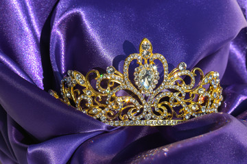 Goldene Tiara Krone mit Steinen auf lila Stoff königliche Hochzeit