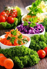 Composition with four vegetable salad bowls on wooden table
