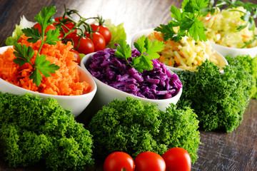 Composition with four vegetable salad bowls on wooden table