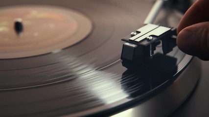 Gramophone and record to listen to. Included gramophone and torque plate close-up on a light background with bright lights. Hand puts needle on vinyl record - Powered by Adobe