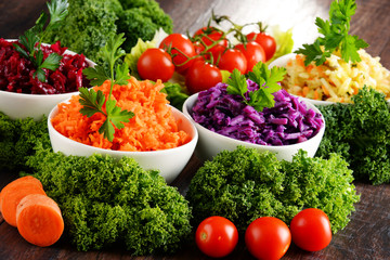 Composition with four vegetable salad bowls on wooden table