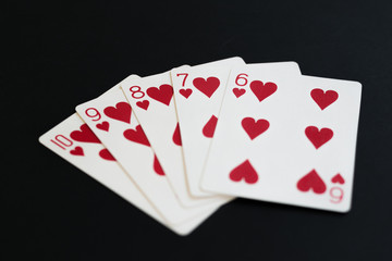 Straight Flush of hearts in poker cards game on a black background