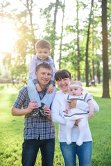 Young parents with children walk in the summer park