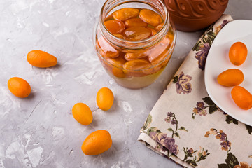 Homemade kumquat jam in  jar and fresh  kumquats, close up