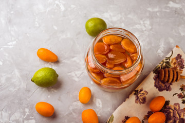 Homemade kumquat jam in  jar and fresh  kumquats, close up