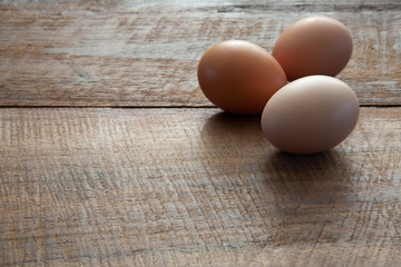 Three Fresh Farm Chicken Eggs on Dark Brown Rustic Wooden Table