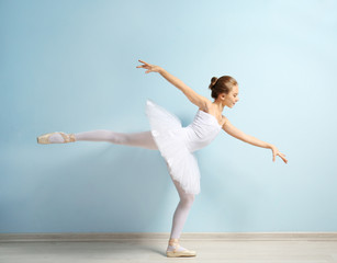Young beautiful ballerina on wall background
