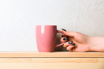 pink tea or coffee cup in hand on white background