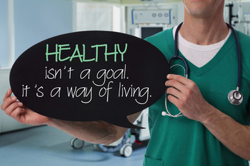 Male doctor holding health inspiration motivation quote on blackboard.