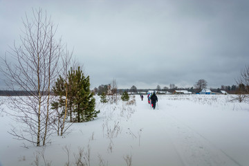 A small group of tourists walking in the field toward the village.