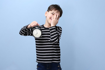 Cute little boy with alarm clock on color background