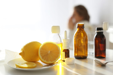 Medicines and lemons with blurred ill woman on background