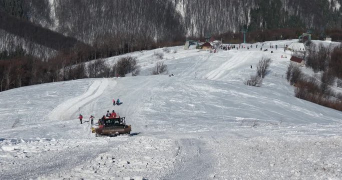 Skiers Riding on the Back of a Snowcat on a Snow Covered Mountain at a Winter Sunny Day