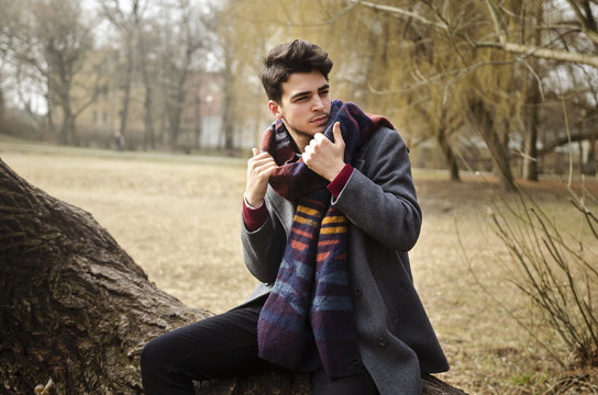 Young Stylish Male Holding Warm Scarf  In Forest On Winter Day